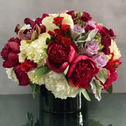 Beverly Hills Florist presents an arrangement that is sure to wow and its available for same day delivery! Our floral piece includes peonies, lavender and white and red roses, cymbidium orchids , nested on hydrangeas in a black cylinder vase. A stunning decoration for any home or office! Or a romantic gesture of love !