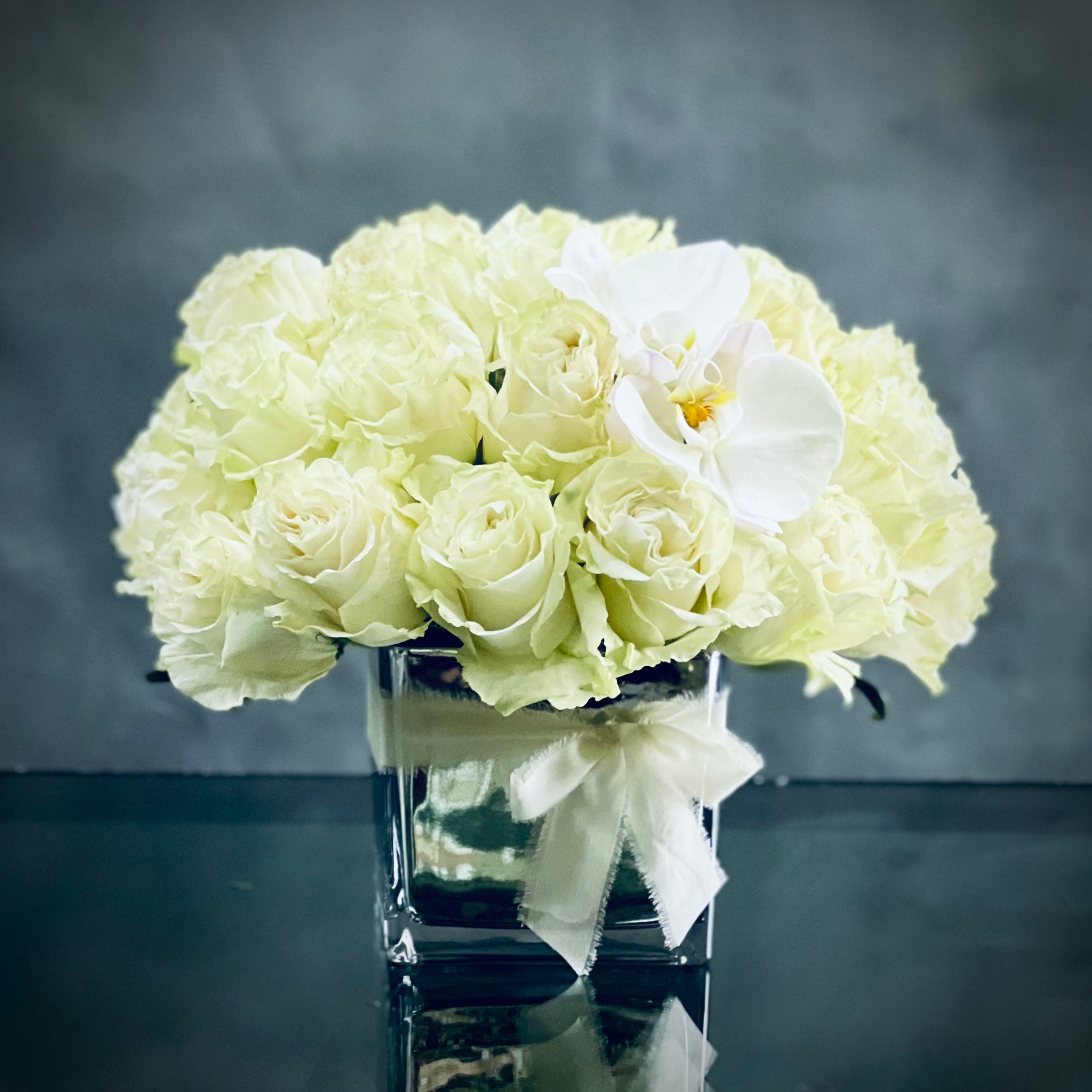 IMG_2395 This arrangement presented by Beverly Hills Florist offers Kissing Butterflies for same day delivery. It has over 30 Blooms of pale green white Roses accented with kissing White Orchids in a 6 inch Mirrored vase. A beautiful arrangement for Sympathies and thinking of you.