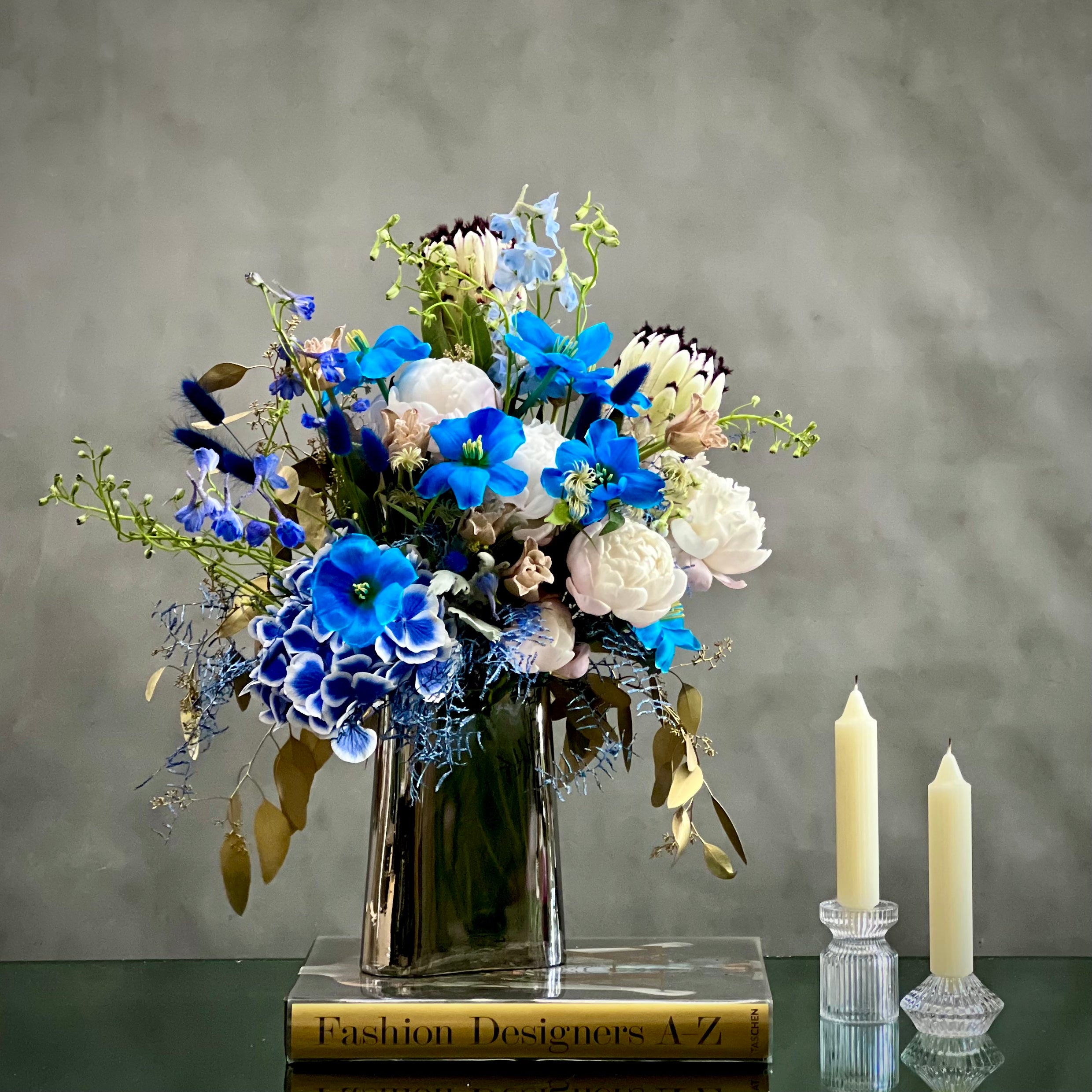 King_protea_white_peonies_blue_tulips When your Monday's are feeling rather blue. Why not try this quiet little bouquet from Beverly Hills Florist to bring a bit of serenity into your week with same day delivery service. This sure to never disappoint, these wonderful selections of blues tulips, white peonies, and white king protea are there to brighten even the gloomiest of days.