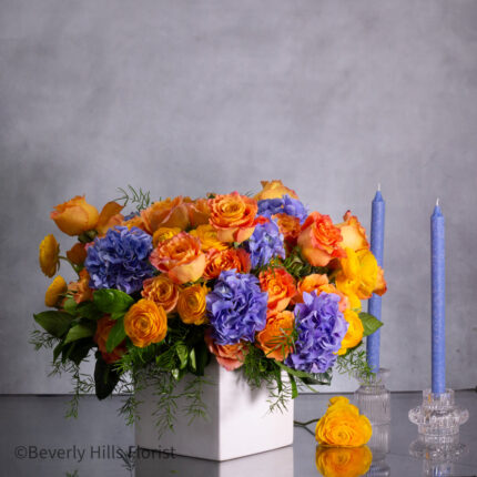 The Tale of Orange Roses and Blue Hydrangeas Arrangement
Luxury Orange Garden Roses and Blue Hydrangeas in White Vase
Sunburst Floral Arrangement for Same-Day Delivery Beverly Hills
Vibrant Orange and Blue Floral Arrangement Los Angeles Delivery