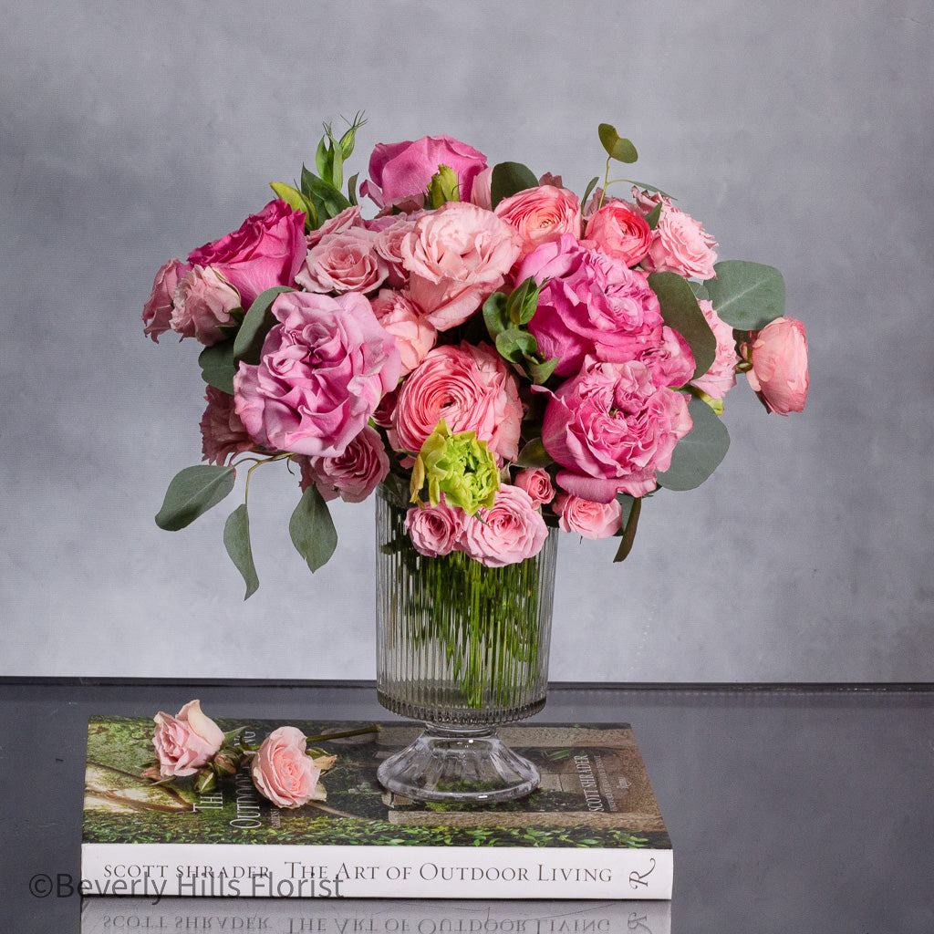 a-case-of-hot-fever-garden-roses-ranunculus-clear-vase.2 A Case of Hot Fever arrangement featuring fresh garden roses and ranunculus in a tall clear vase, designed in a circular formation, perfect for all occasions.