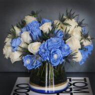 Blue Me Away arrangement with blue and white roses, thistles, and colored sand in a modern vase, available for same-day delivery by Beverly Hills Florist.