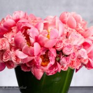 Luxurious arrangement of coral peonies and pink spray roses in a pedestal vase, available for same-day delivery.