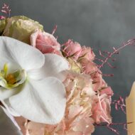 Dancing on the Clouds arrangement featuring soft pink hydrangeas, roses, spray roses, and white orchids in a chic white ceramic vase, perfect for all occasions.