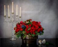 Round Christmas Gift Box with roses, amaryllis, thistle, tulips, orchids, seasonal greens, berries, pine cones, and champagne, available for same-day delivery in Los Angeles.